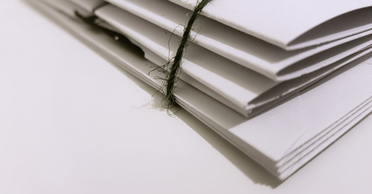 Pile of white envelopes tied with a green string, showcasing a minimalist design.