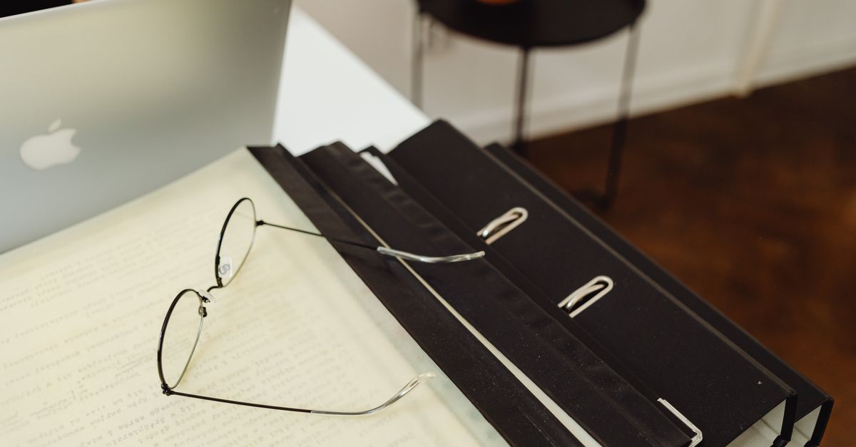 A neat office setup with binders, eyeglasses, and a laptop, perfect for productivity.