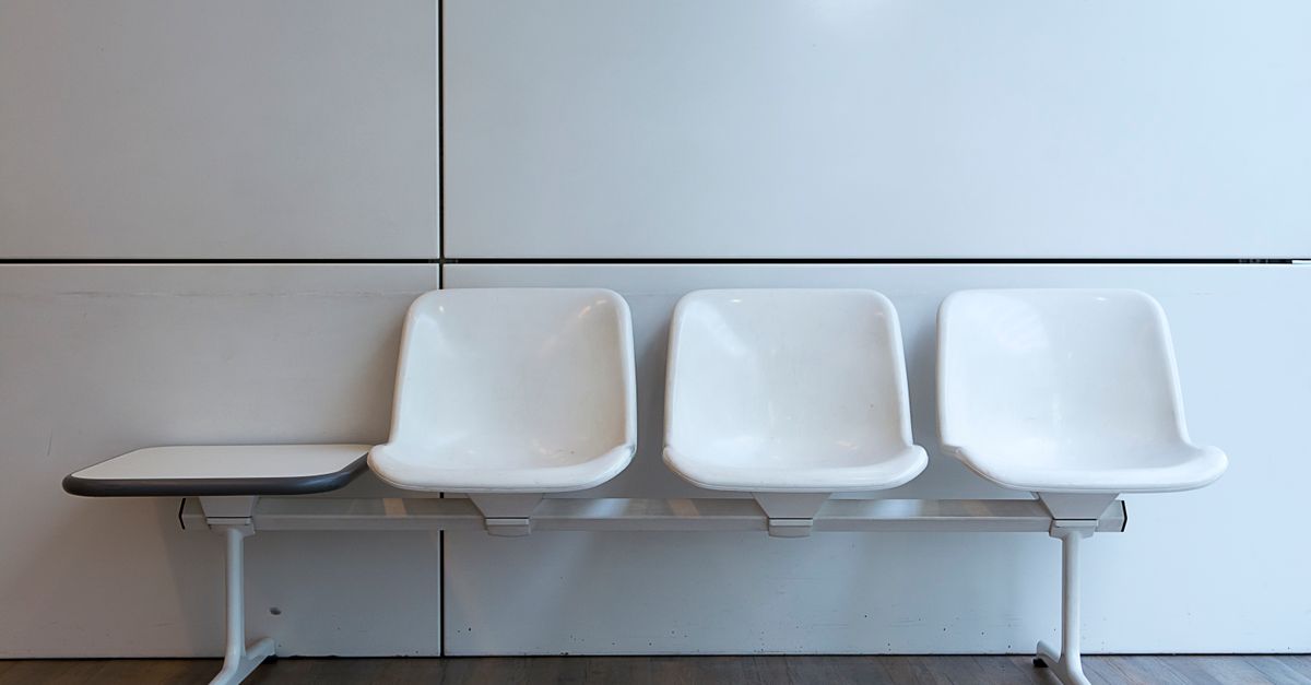 A minimalist setup of white plastic waiting room chairs in a modern interior.