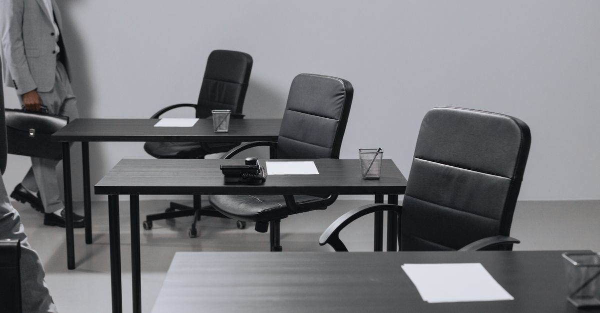 Contemporary office space with black leather chairs and desks, showcasing a minimalist design.