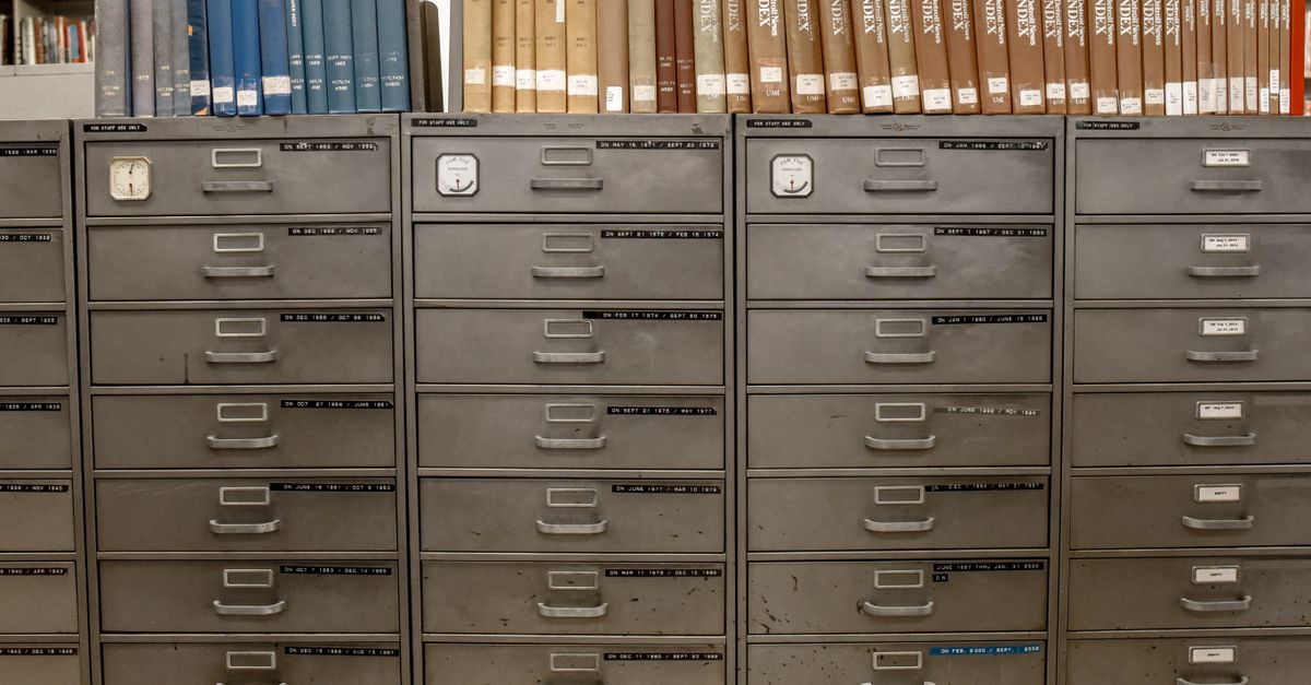 Organized filing cabinets stacked with indexed books in a library setting.