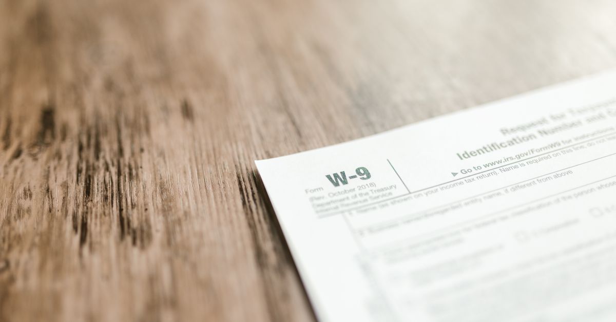 A close-up of a W-9 tax form placed on a wooden desk, emphasizing paperwork and finance.