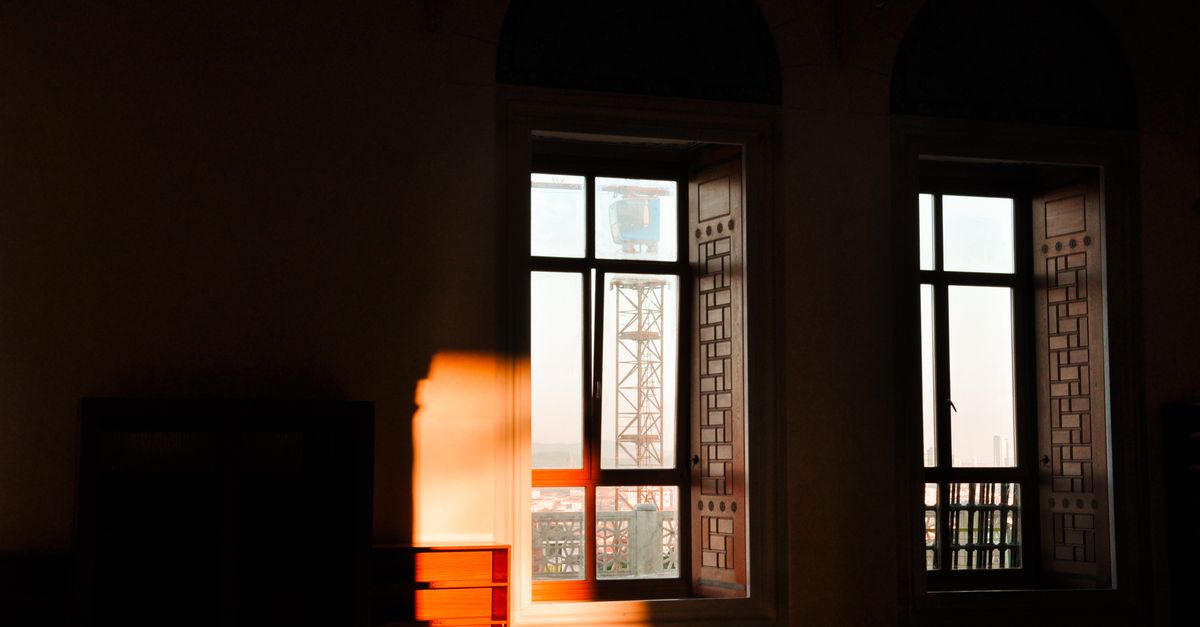 A room bathed in warm sunlight with decorative windows, featuring a city view through the glass.