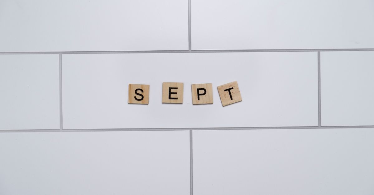 Wooden letter tiles spelling 'Sept' on a white tiled background, perfect for autumn themes.